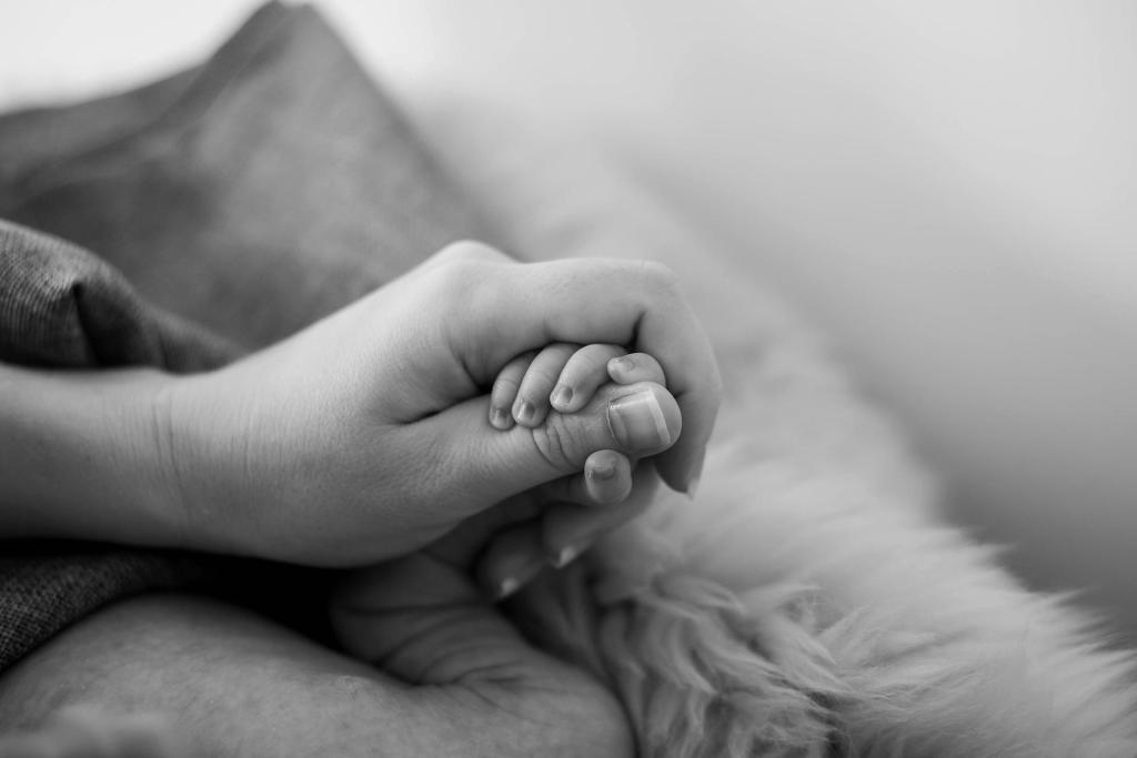 a mother holds her baby's hand