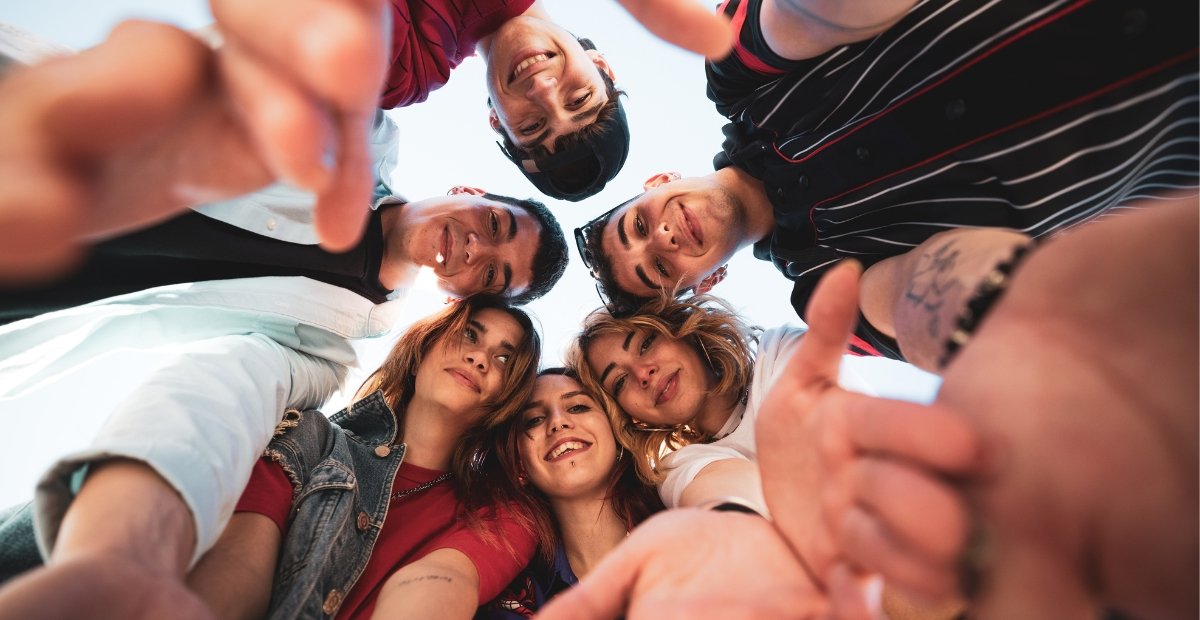 young adults huddled together staring down at a camera
