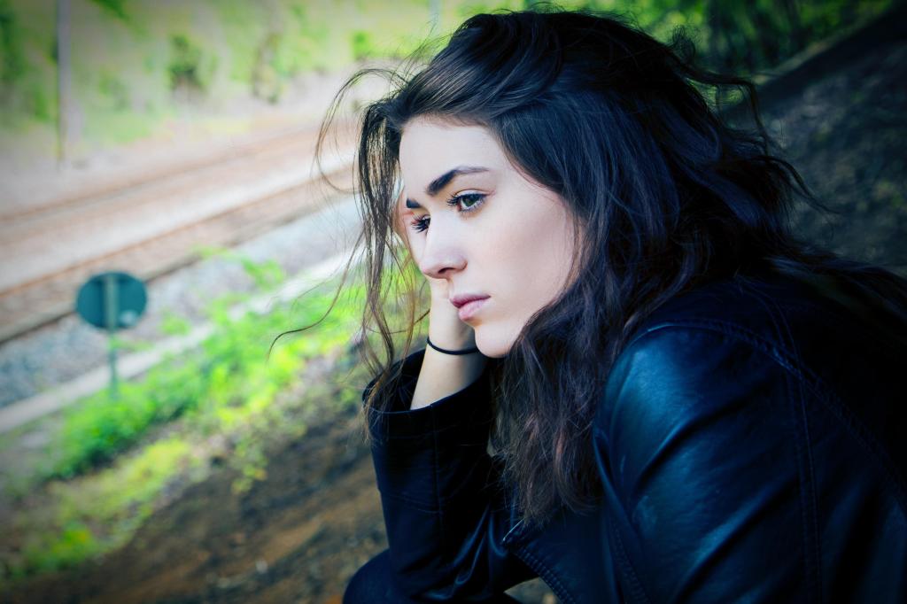 a woman with dark hair looks out over an overgrown street