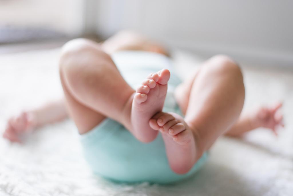 close up of baby's feet and legs while lying on the floor