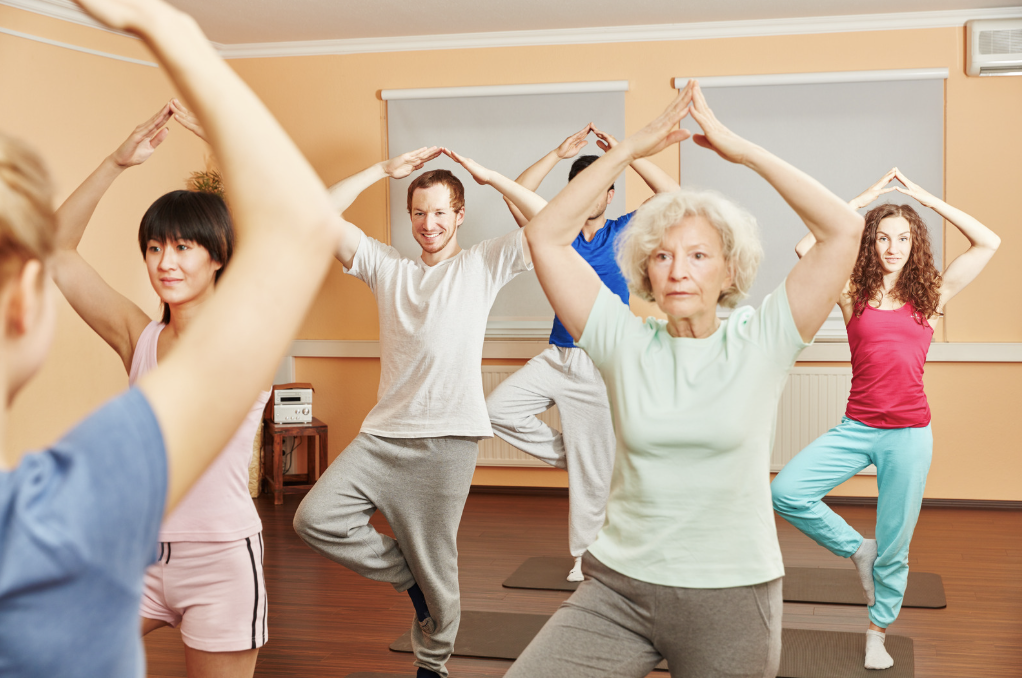 Older woman practicing yoga in a studio filled with younger people
