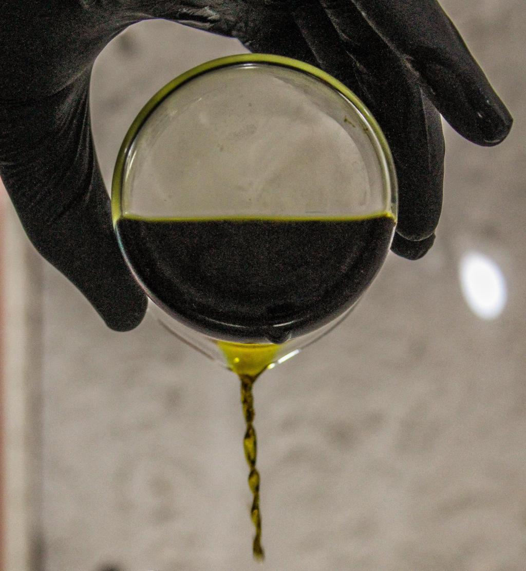 someone pouring black liquid out of a beaker