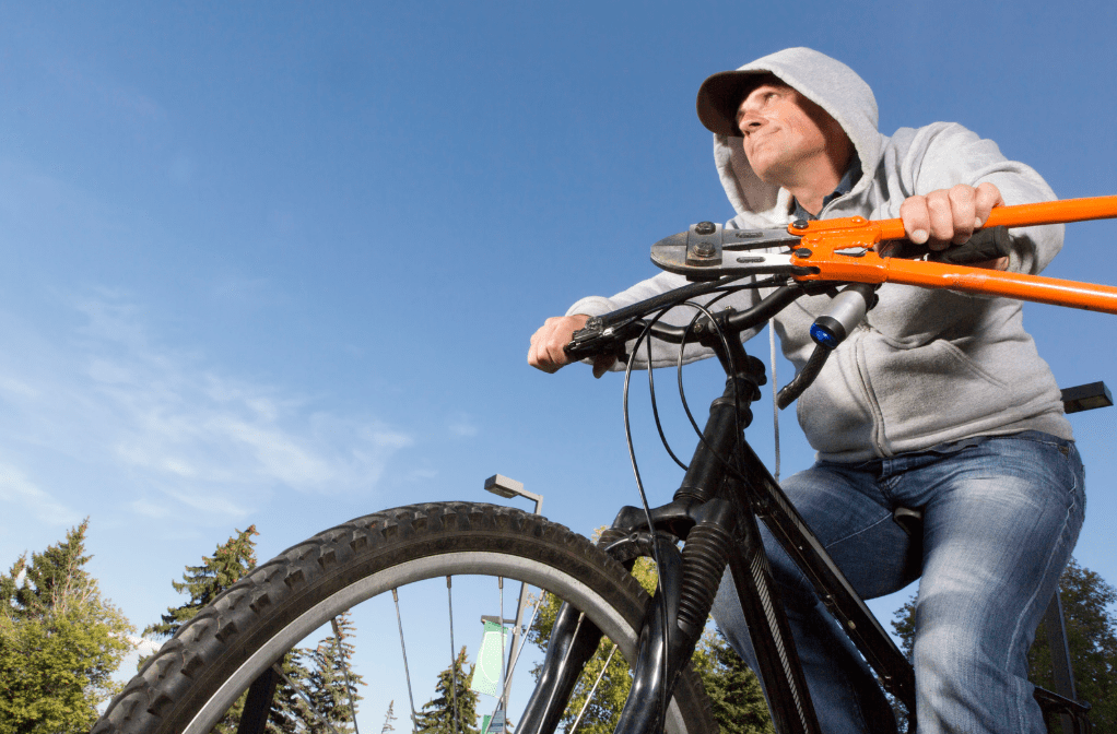 Man in a hoodie with pliers riding a bike.