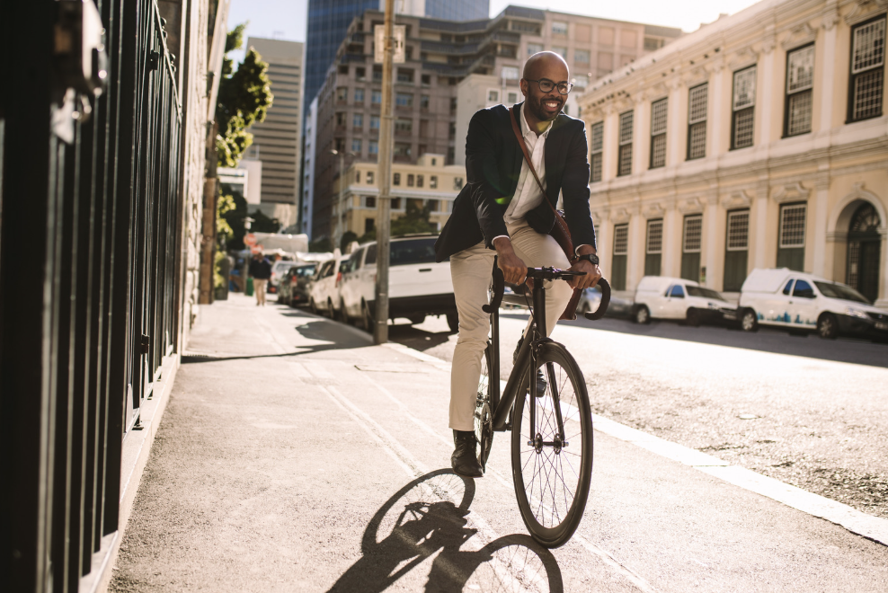 A man in formal clothes riding a bike on the sidewalk