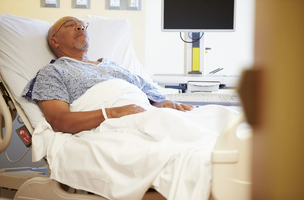 An older man sleeping in a hospital bed