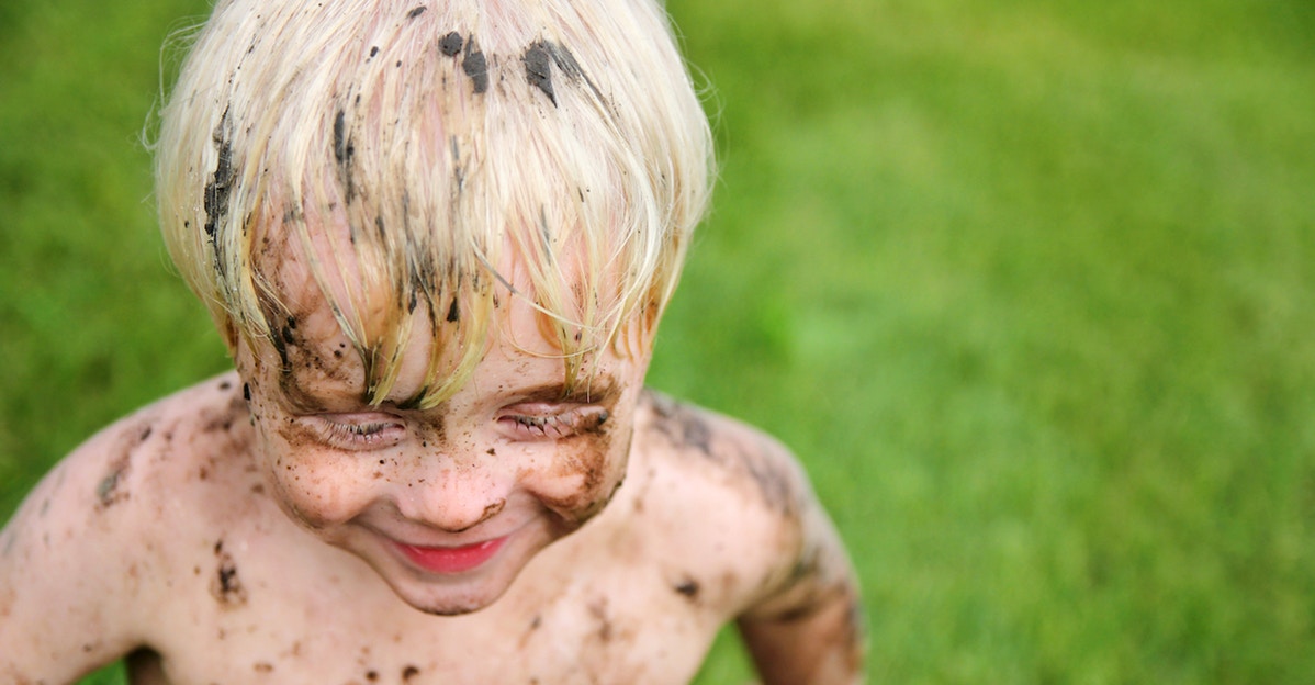 little boy outside covered in mud