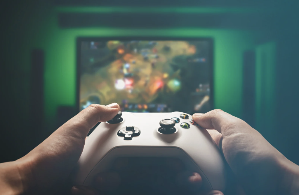 Hands on a video game controller in front of a TV