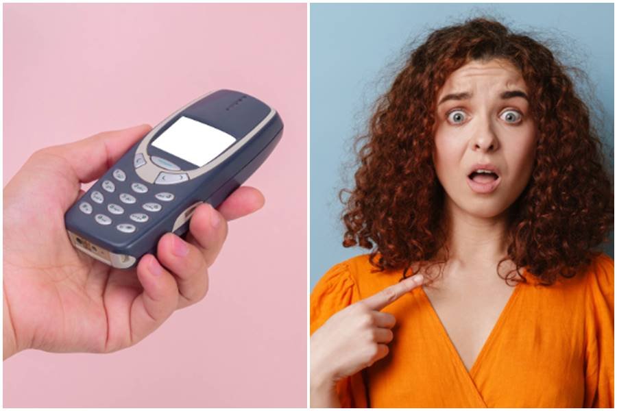 someone holding phone; woman points at self in surprise