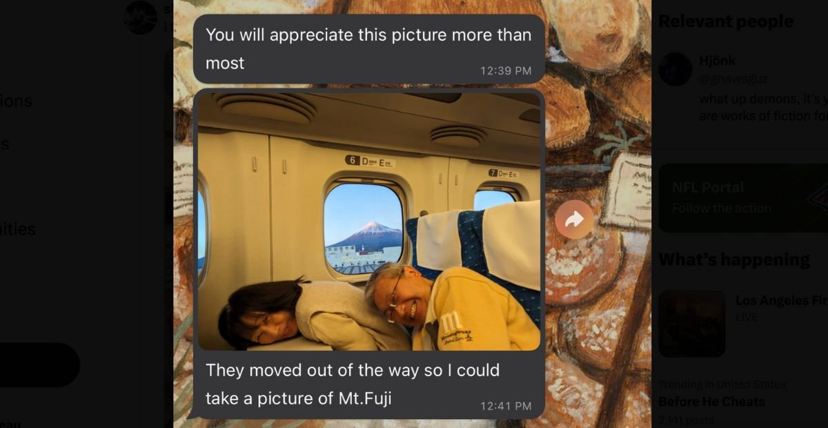 couple smiling and ducking down in front of a window with a view of mt fuji