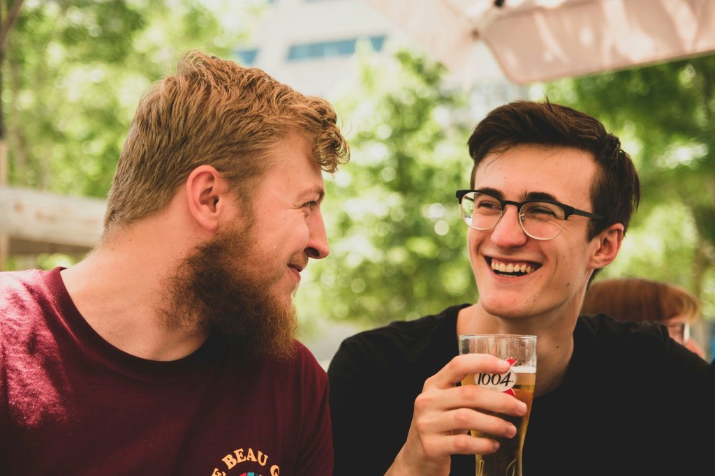 two men talking, drinking beer