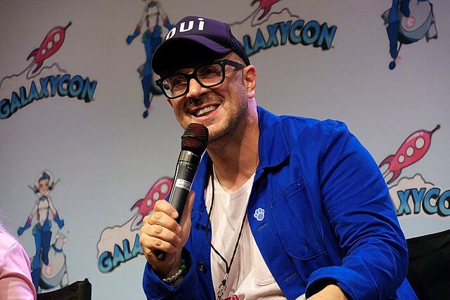 Steve Burns smiling and holding a microphone