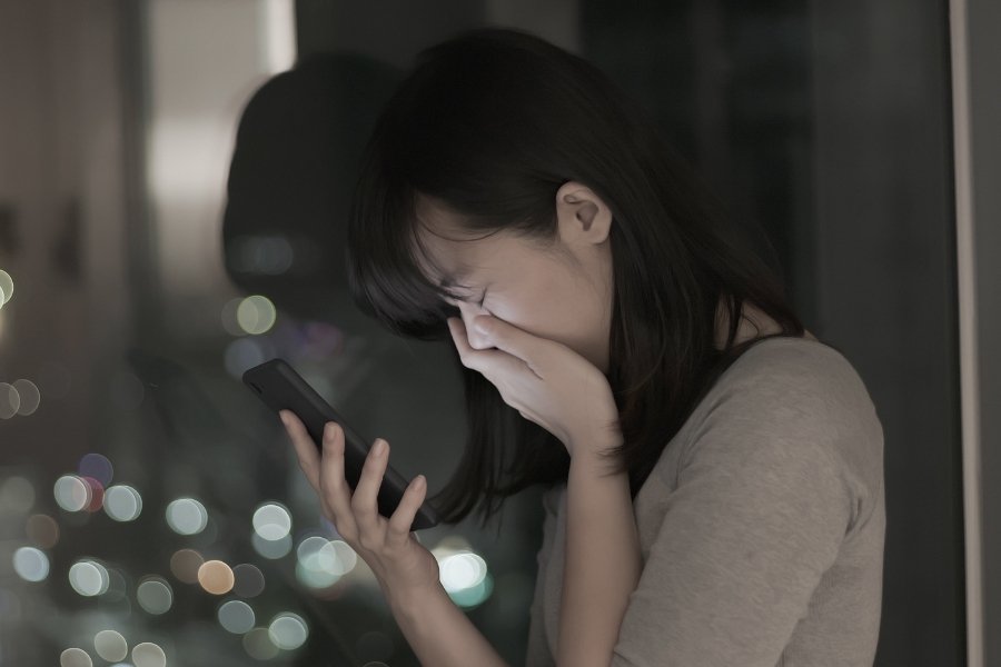 woman holding her hand over her mouth while holding a cell phone