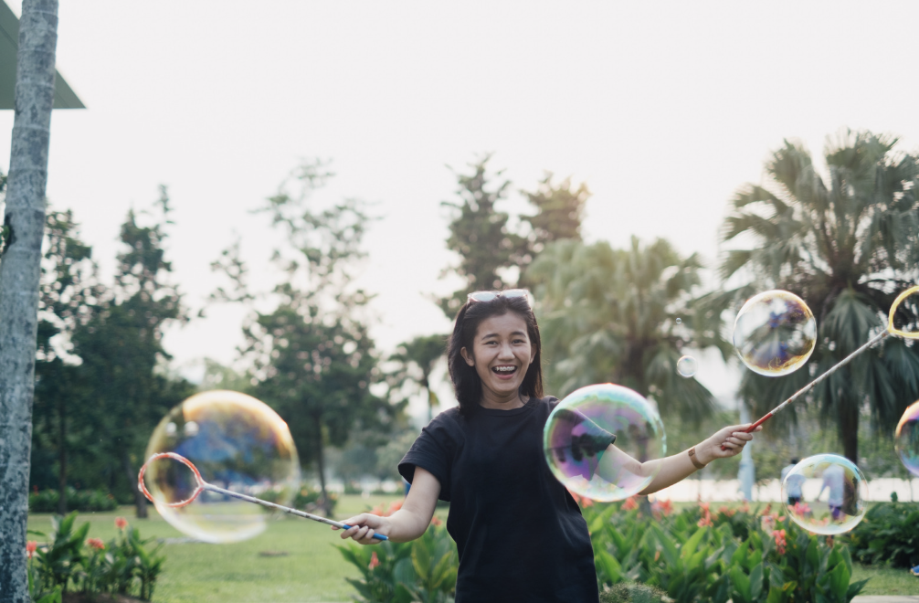 Woman making large bubbles and smiling.