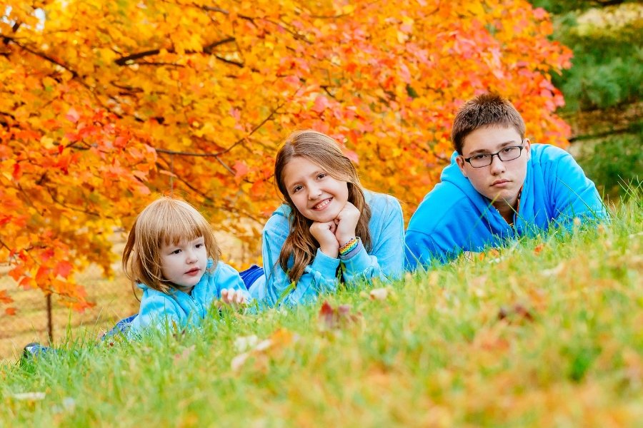 three siblings lying in the grass