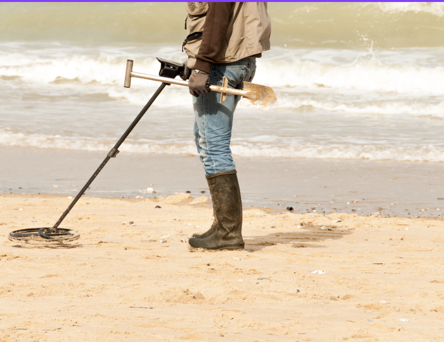 Person using a metal detector on the bach