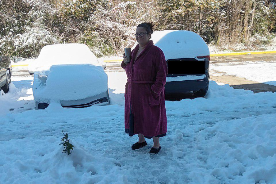 A woman stands outside in the snow.