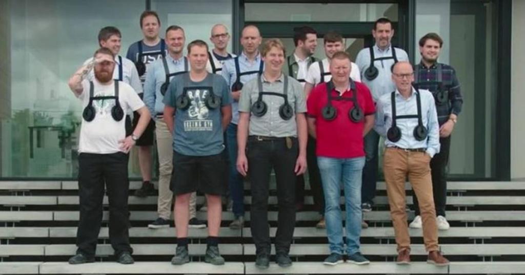 group of men wearing "breast weights" pose for group picture on steps.