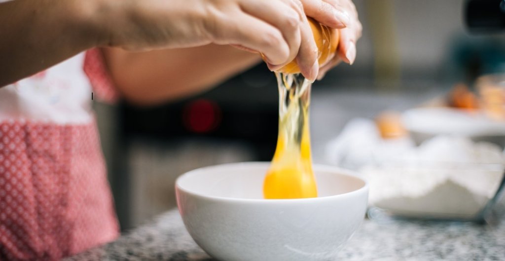 someone cracking an egg into a bowl