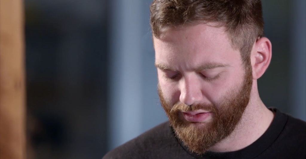 bearded man looking troubled while reading.