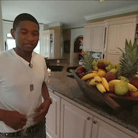 gif of singer Usher lifting his shirt to show off his abs