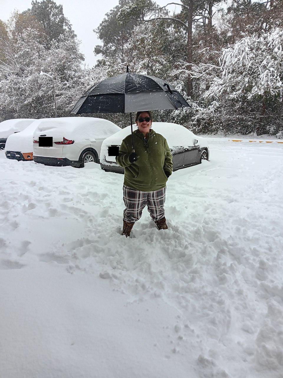 Alishia stands in the snow with an umbrella.