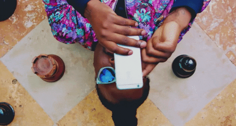 Person lying down, wearing sunglasses, taking a selfie with a phone.