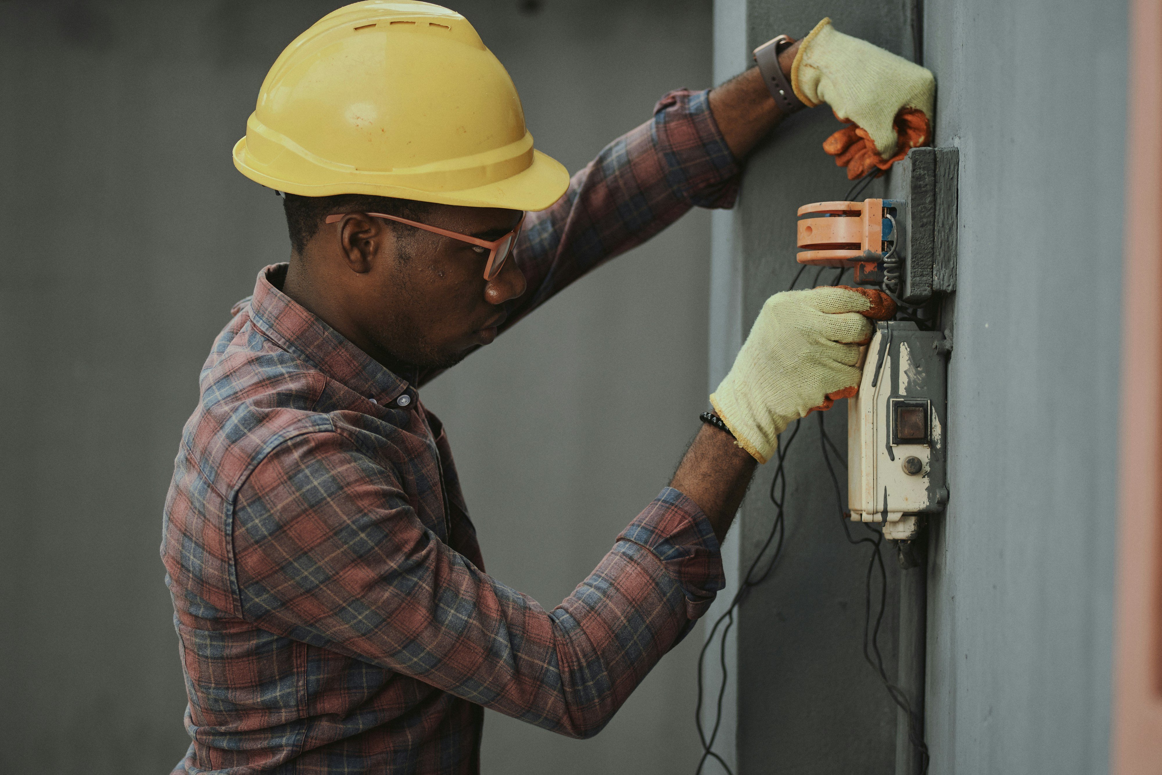 A man in a hard hat inspects an electrical box