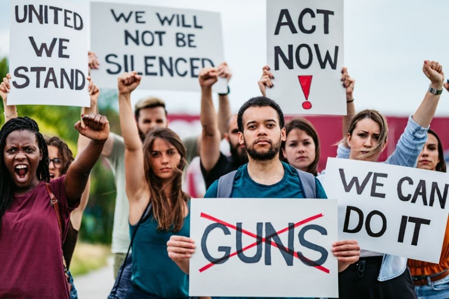 Protesters, holding signs, advocating unity, action, anti-gun sentiments