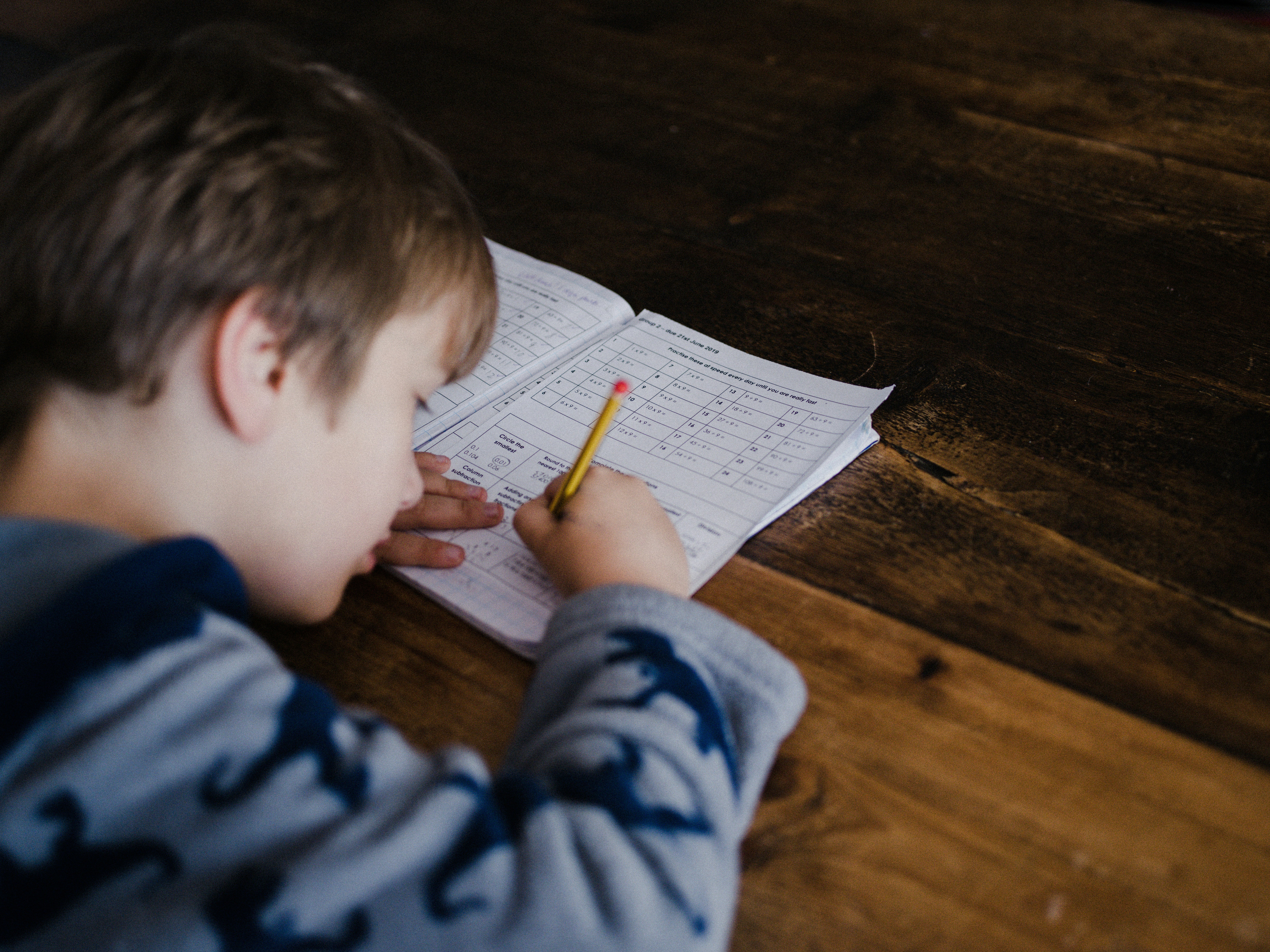 a boy doing schoolwork at wooden desk