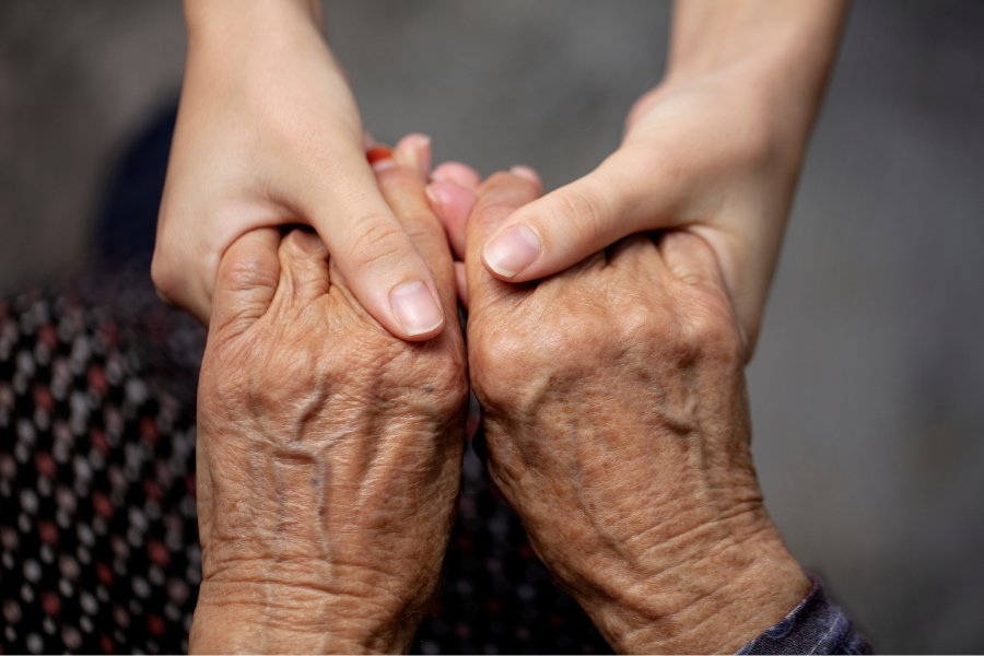 older person's hands holding a younger person's hands, compassion for elderly