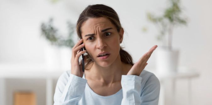 woman on phone, upset woman, confused woman, woman white top, smartphone, brown hair