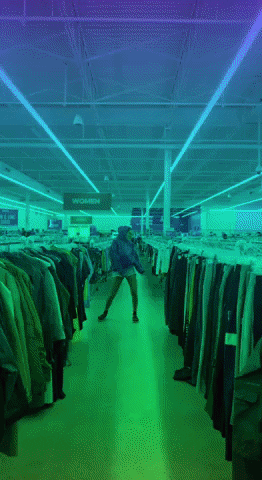 A person dances joyfully at a thrift store.