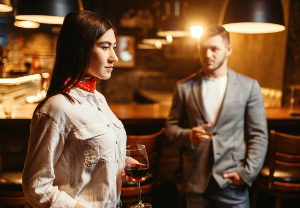 A man stares at a woman at a bar.