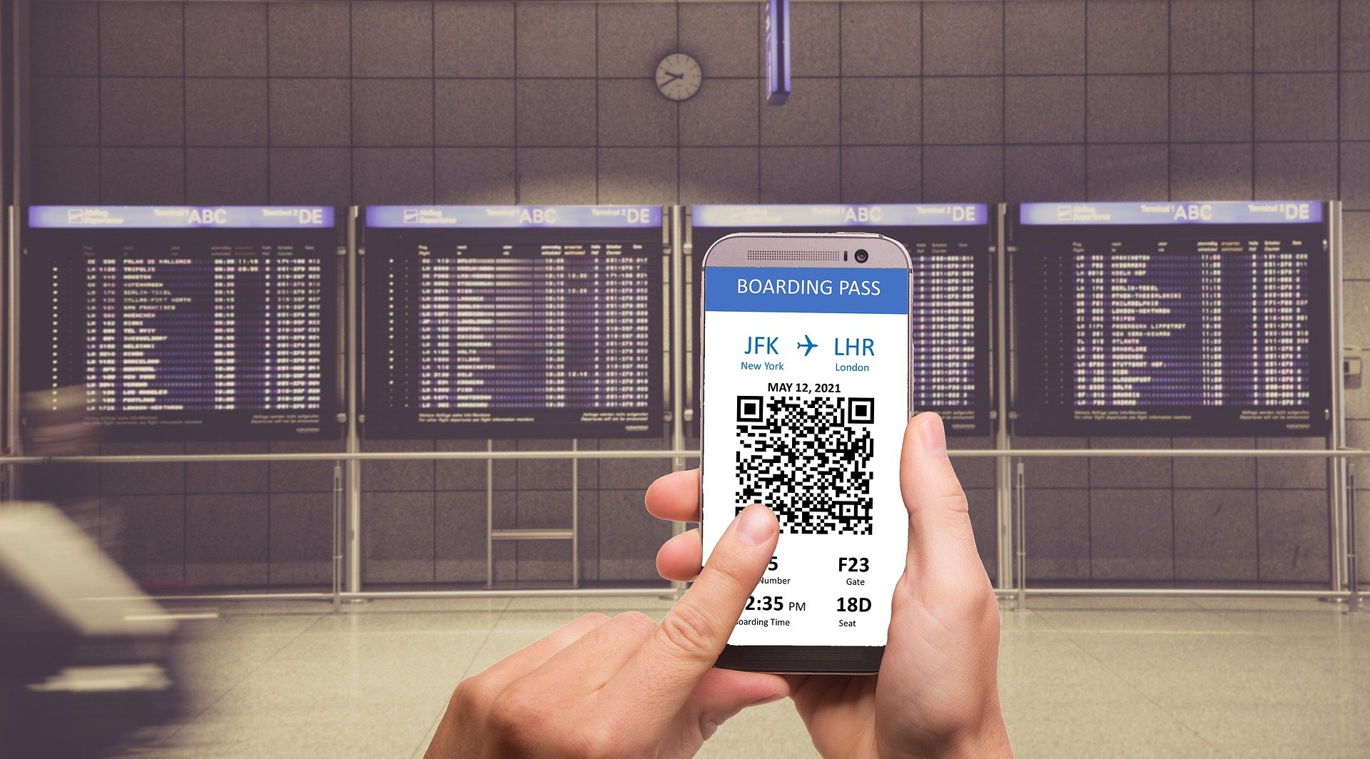 a boarding pass on someone's smartphone in front of flight board
