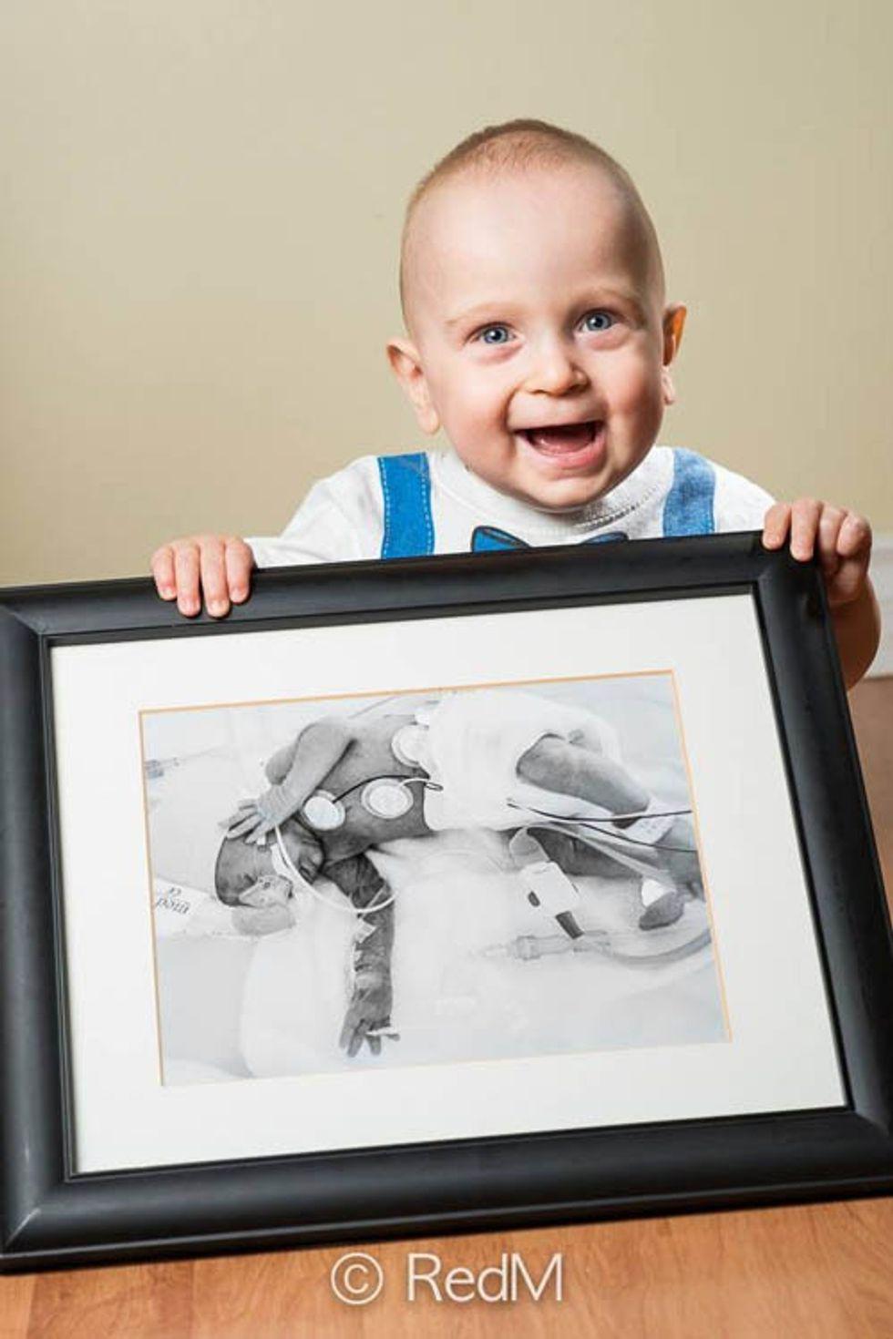 a young boy holds a black and white photograph of himself as a premature baby