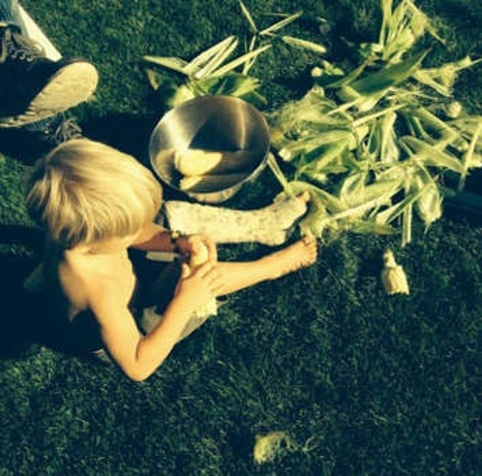 young boy in a cast sitting by corn stalks