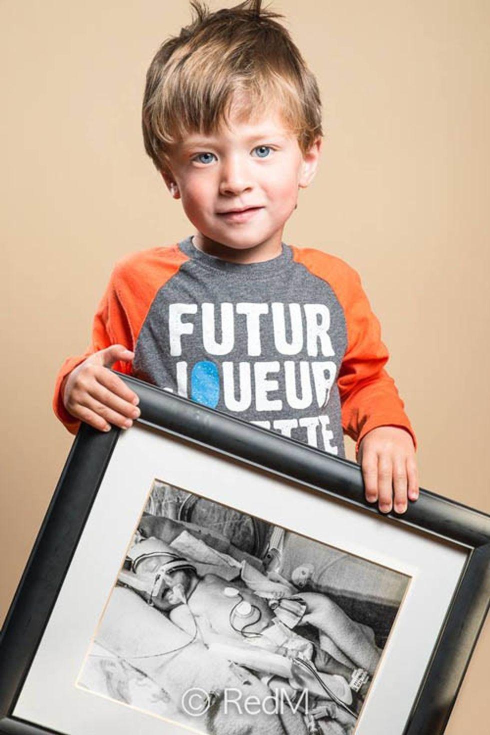 a young boy holds a black and white photograph of himself as a premature baby