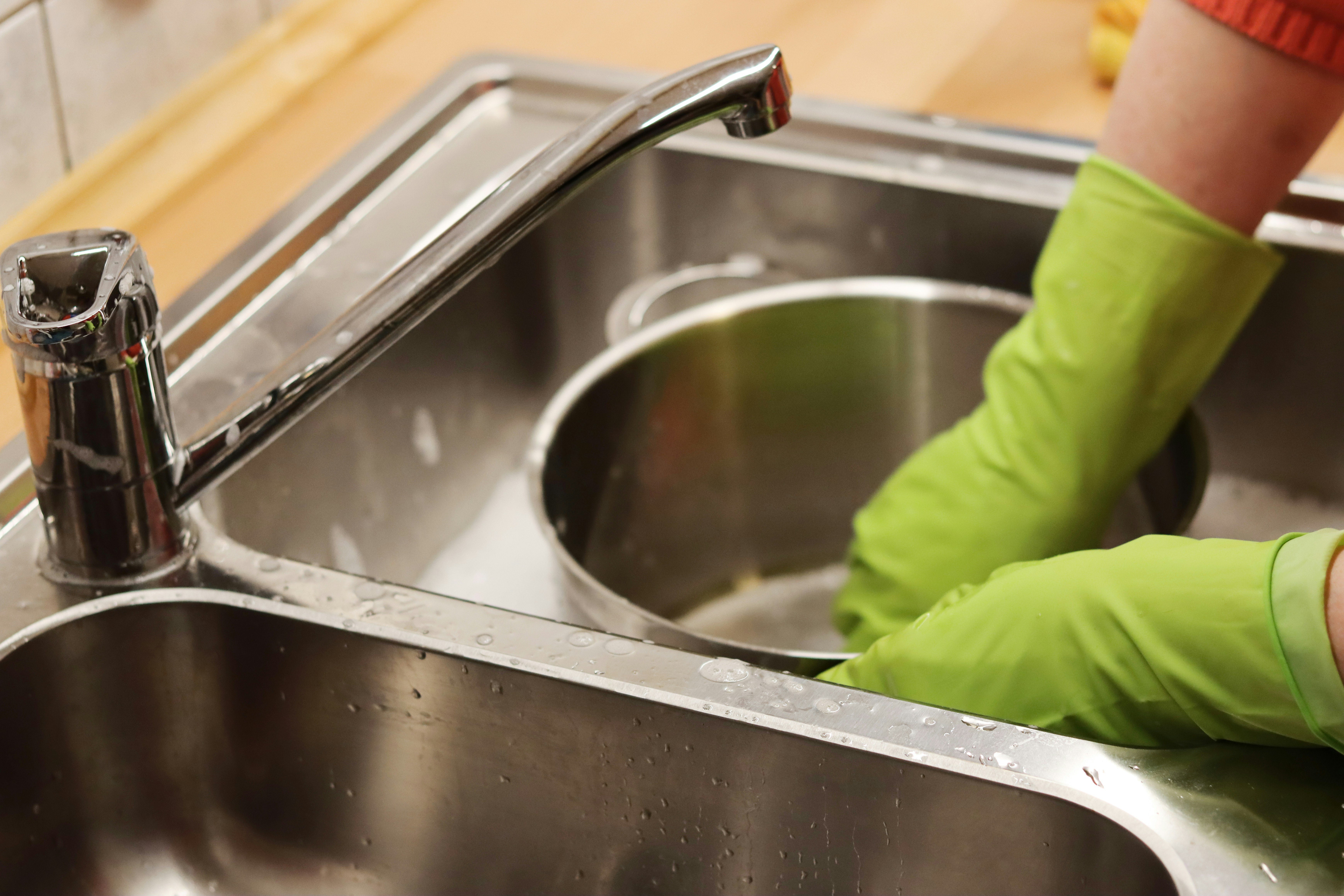 someone scrubbing a pot in a kitchen sink