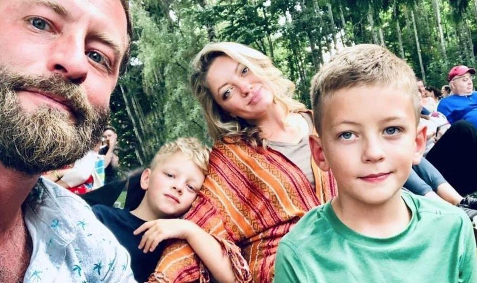 Young family takes photo outside.