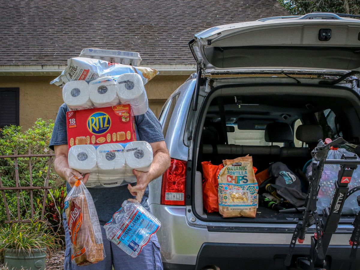 man pulling food and toilet paper out of the car