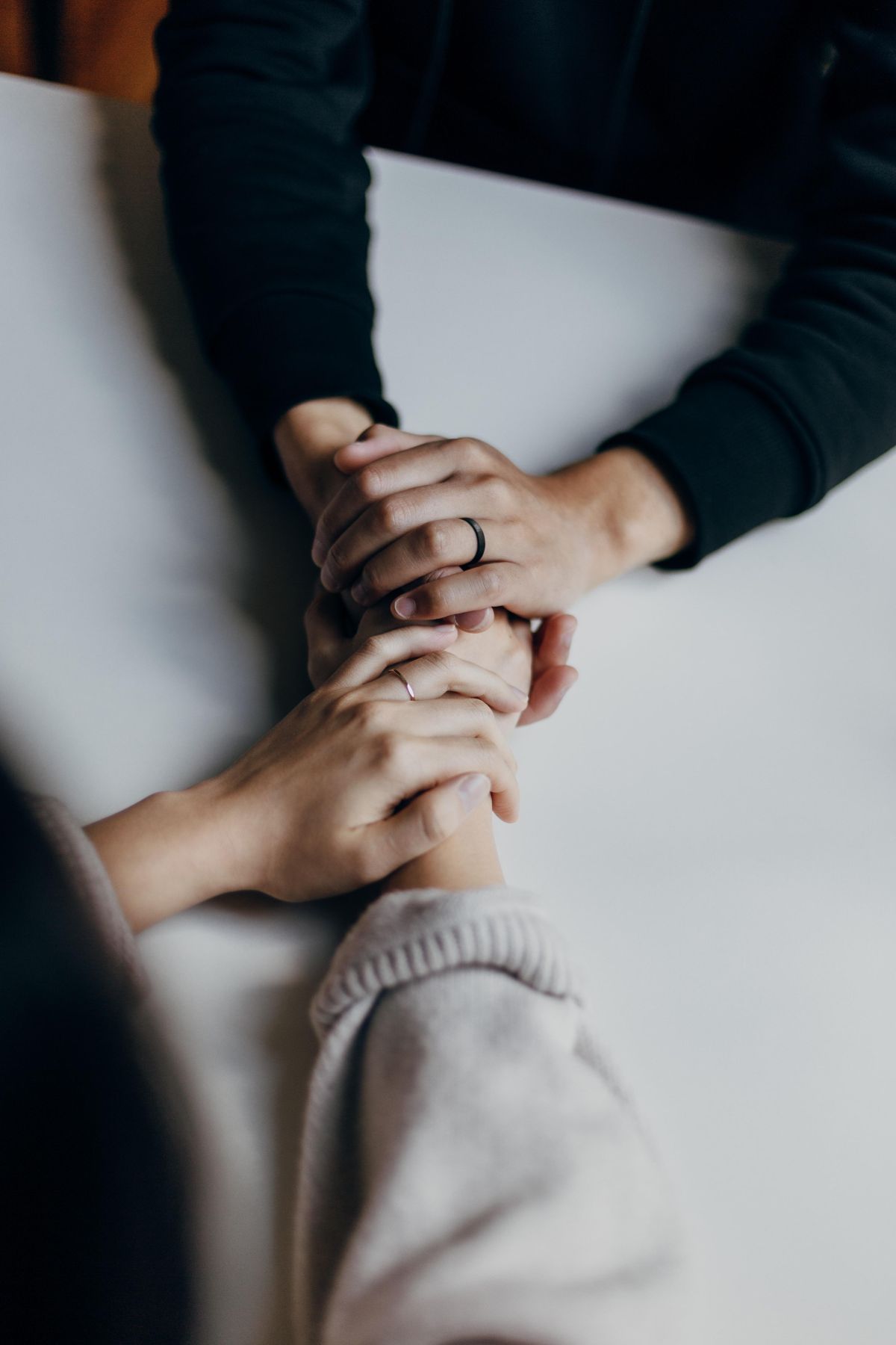person in black long sleeve shirt holding hands with person in long cream colored sleeves