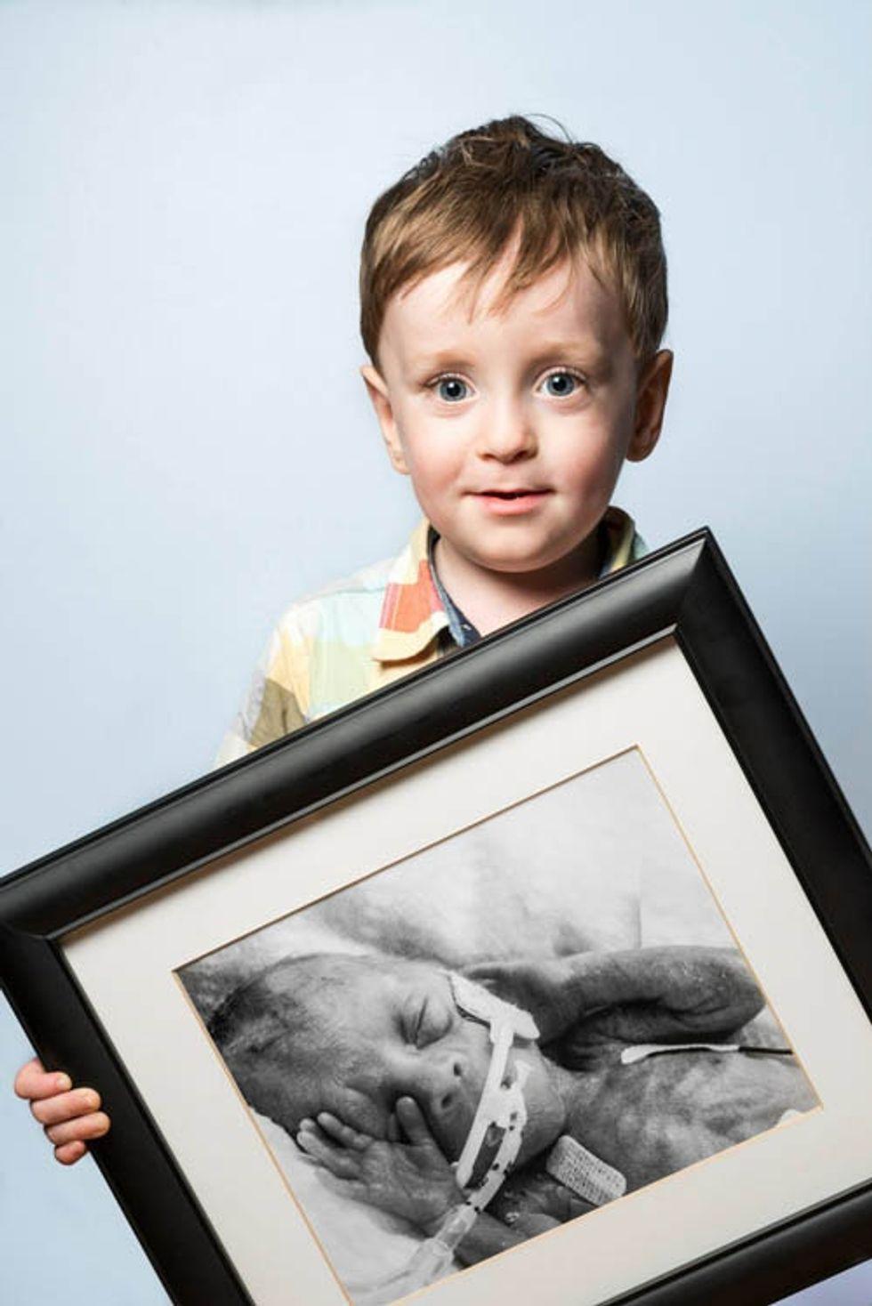 a young boy holds a black and white photograph of himself as a premature baby