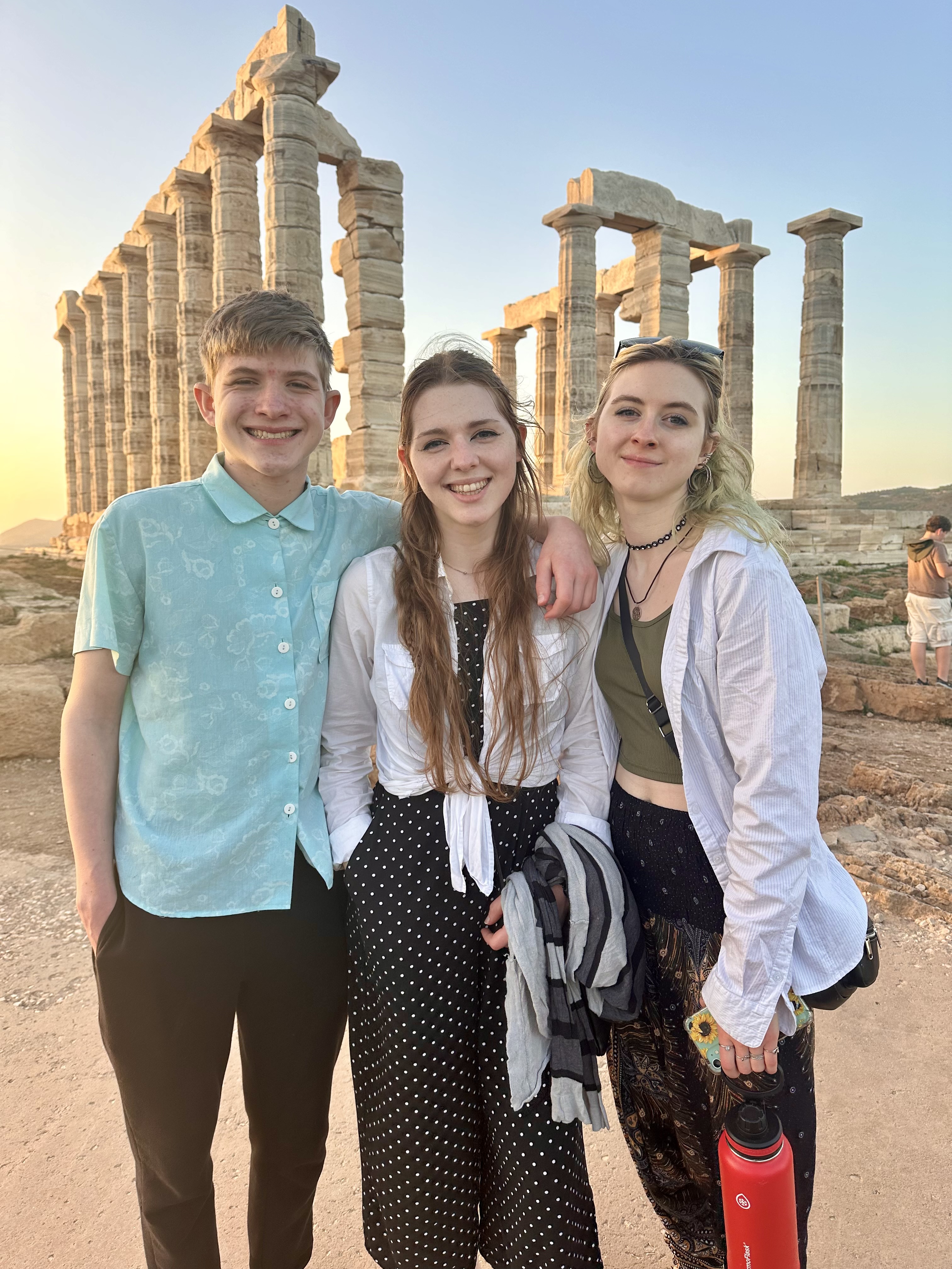 three young people in front of the temple of poseidon
