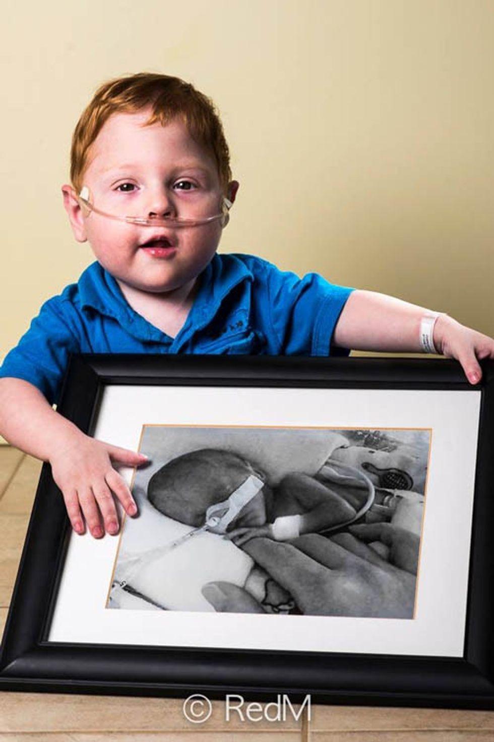 a little boy holds a black and white photograph of himself as a premature baby