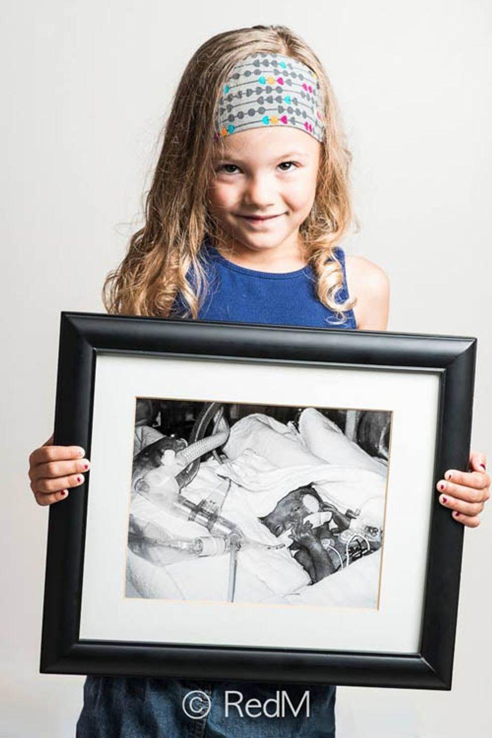 a little girl holds a black and white photograph of herself as a premature baby