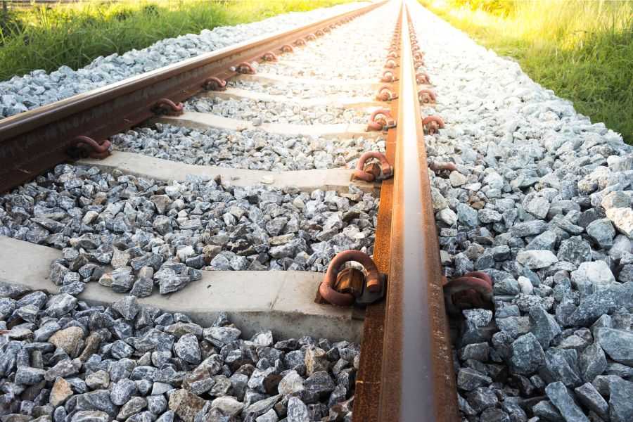 railroad tracks; rocks around train; train; cargo trains; rail road