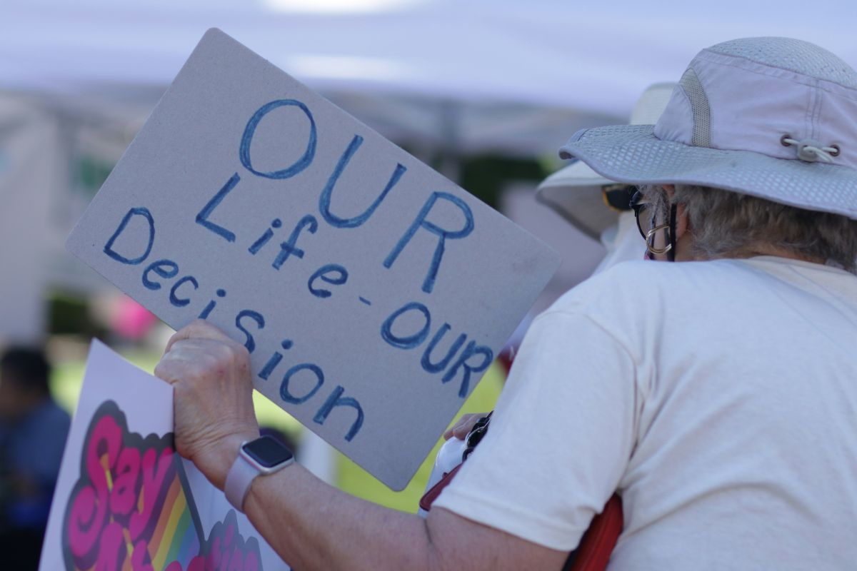 a man holds a sign for pro-choice arguments reading