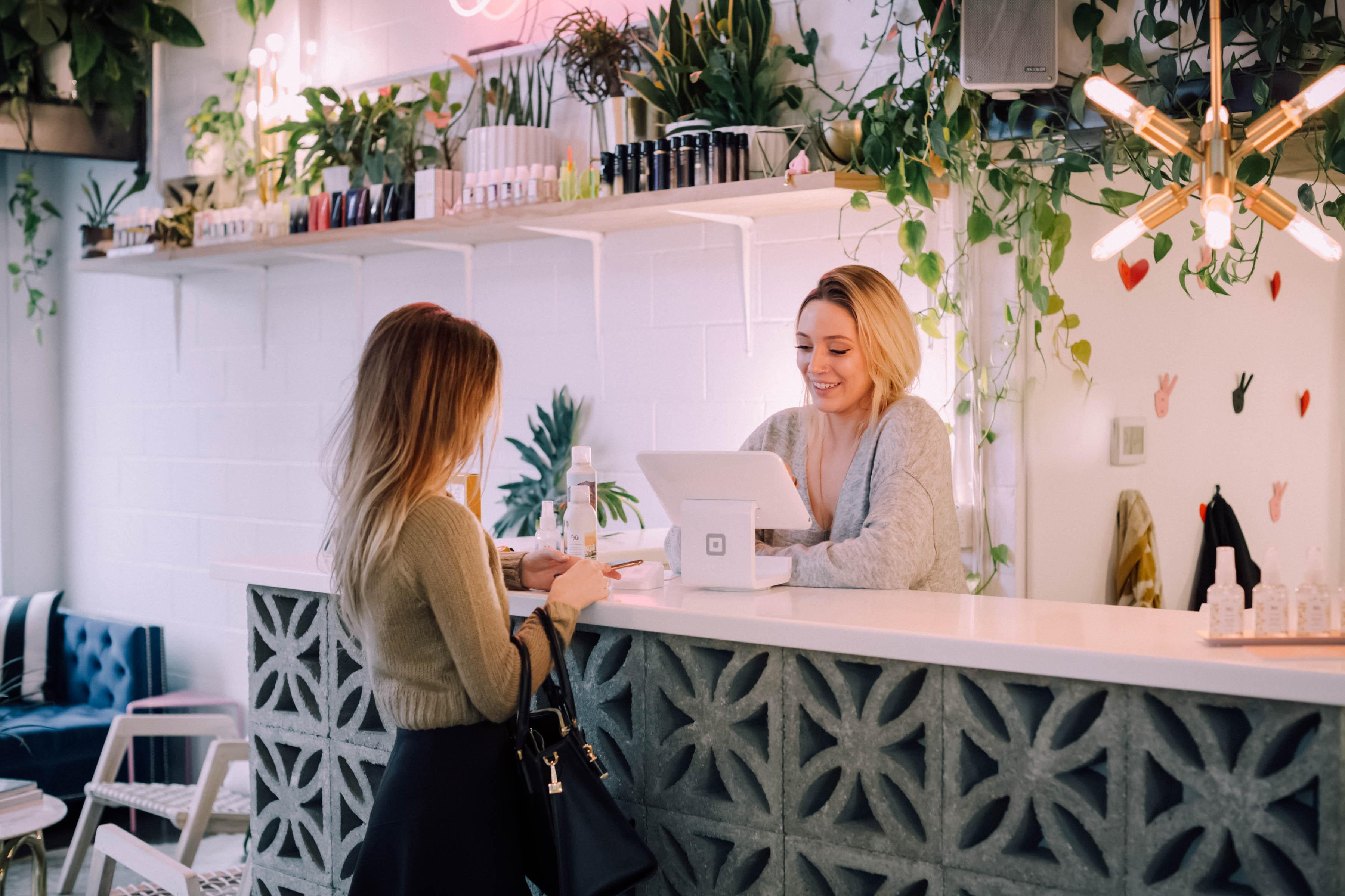 two women on opposite sides of a counter completing a transaction