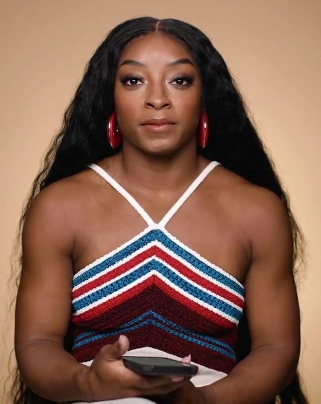 Simone Biles with her hair down looking directly at the camera