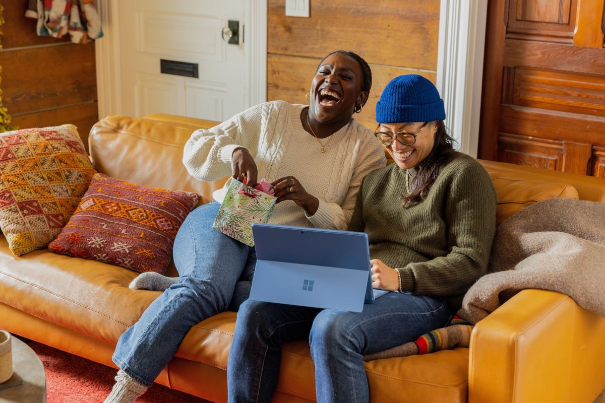 two women sitting on a couch laughing